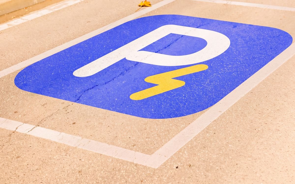 Plaza de parqueo en la calle con el símbolo de Recargados pintado en el piso: una P blanca con un rayo dorado sobre fondo azul.
